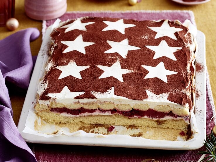 Glühwein-Tiramisu-Schnitten serviert auf einem weißen Teller, daneben weihnachtliche Deko-Elemente. 