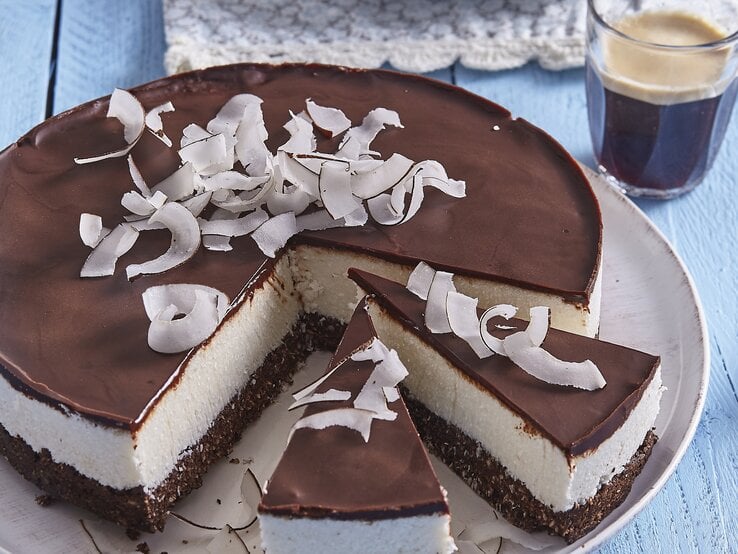 Bounty-Torte mit Kokosraspeln / Glas mit Kaffee / Untergrund Holz / Draufsicht schräg