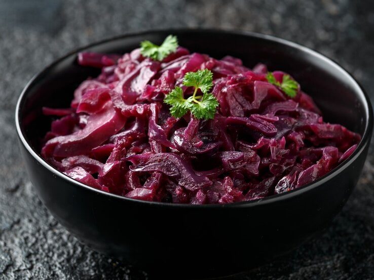 Eine schwarze Schale mit Rotkohl auf einem dunklen Tisch.