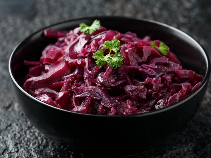 Eine schwarze Schale mit Rotkohl auf einem dunklen Tisch.