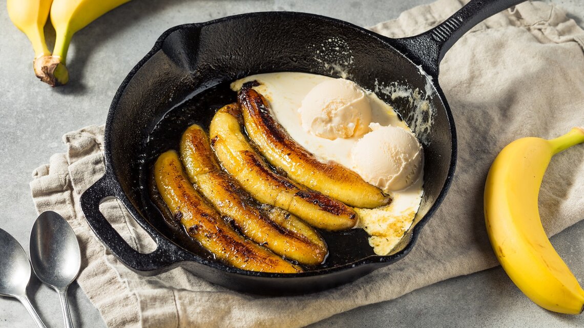 Eine Pfanne mit Rum-Bananen mit Vanilleeis.