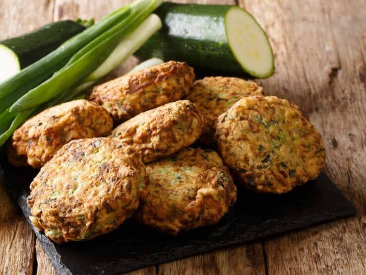 Eine schwarze Schieferplatte mit Zucchini-Feta-Kugeln oben drauf.