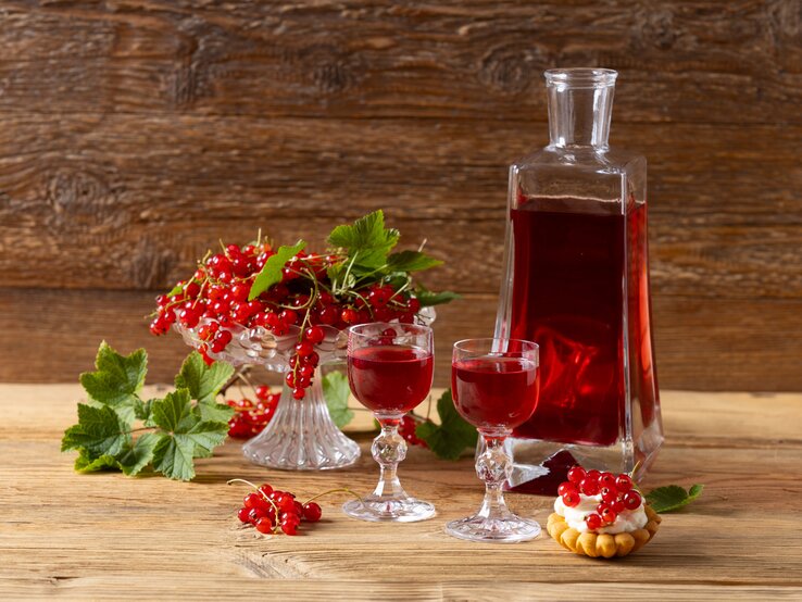 Eine Glasflasche mit Johannisbeerlikör mit Wodka auf einem Holztisch.
