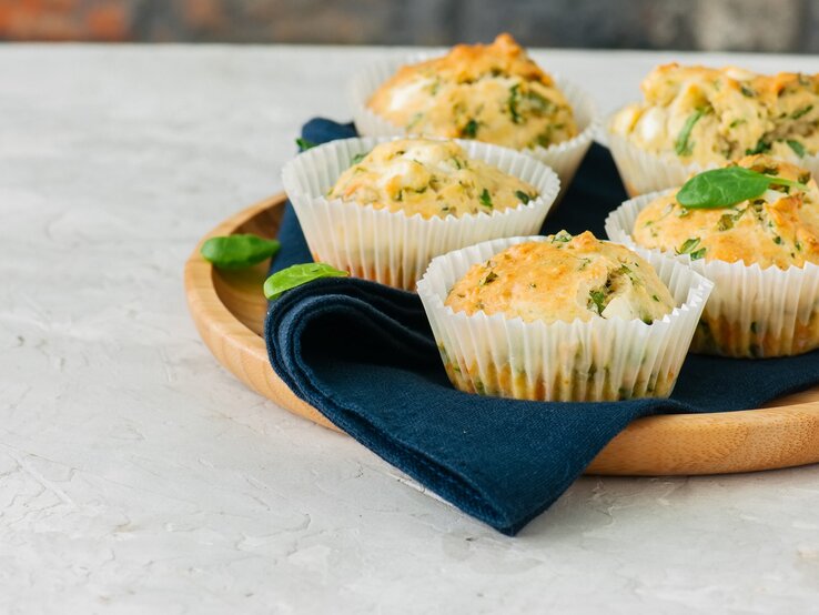 Fünf Pesto-Muffins auf einem Holztablett.