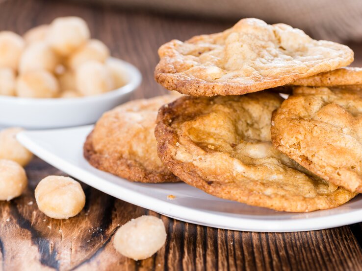 Mehrere Cookies auf einem weißen Teller und Holztisch aus seitlicher Perspektive fotografiert.