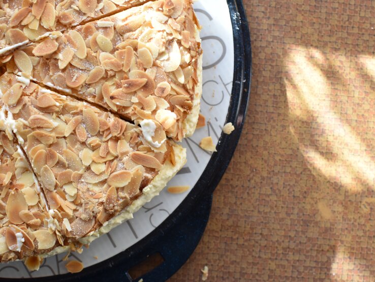 Bienenstich ohne Hefe auf Kuchenplatte auf braunem Untergrund. Alles nah und direkt von oben fotografiert.