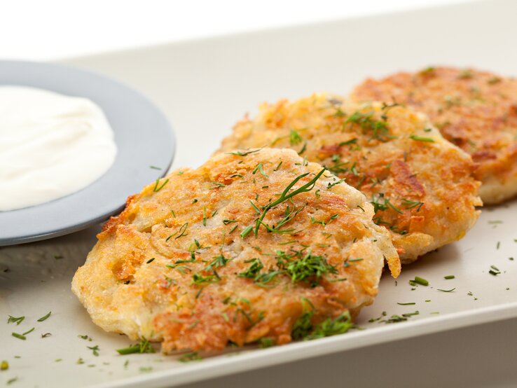 Kartoffel-Käse-Puffer mit Dip auf weißem Teller. 