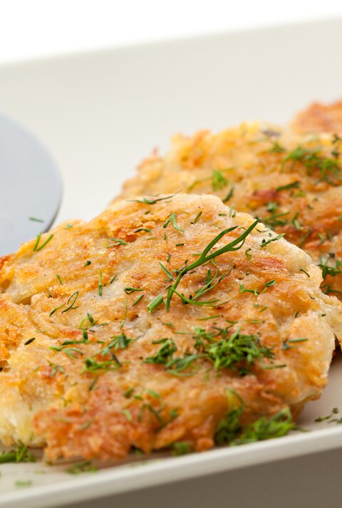 Kartoffel-Käse-Puffer mit Dip auf weißem Teller. 