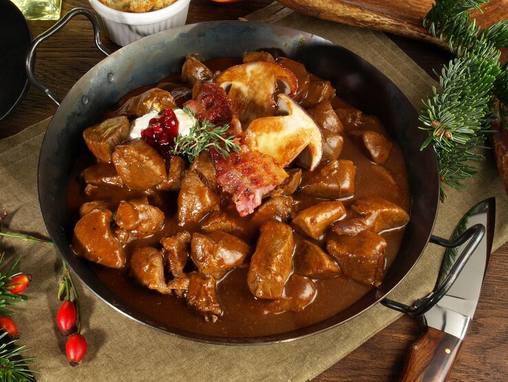 Eine gusseiserne Pfanne mit dem Hirschrahm auf einem Leinentuch mit Tannendeko.