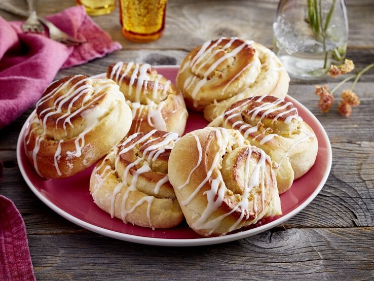 sechs Walnuss-Schmand-Schnecken auf einem teller. Sie sind mit Zuckerguss überzogen. 