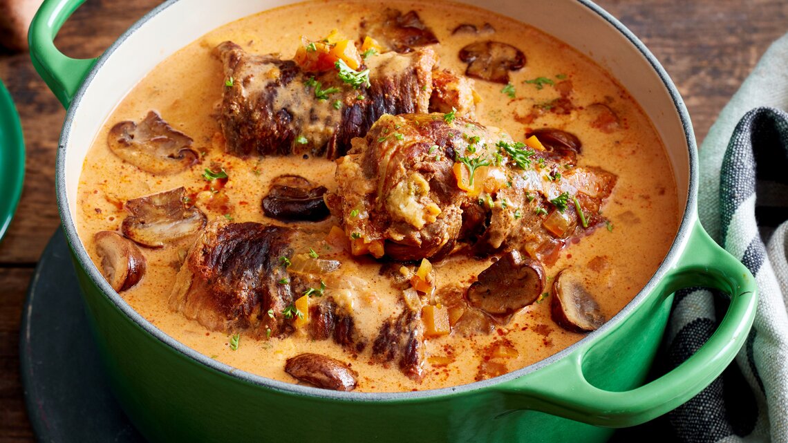 Rindsrouladen mit Knödelmix / gusseiserner Topf / Draufsicht schräg / Untergrund aus Holz