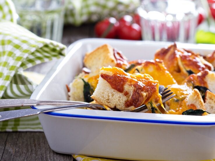 Toast-Mozzarella-Auflauf in weißer Auflaufform, daneben rustikale Dekoration.