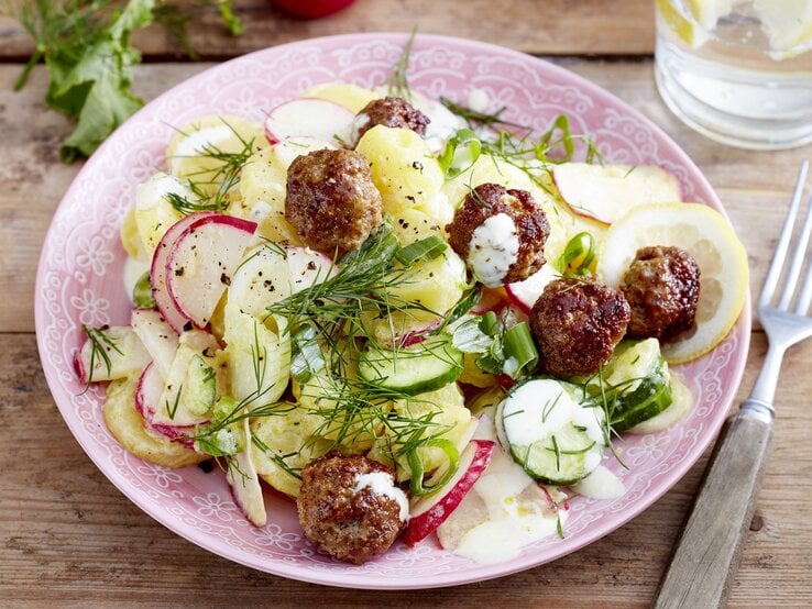 Skandinavischer Kartoffelsalat mit frischem Dill, Skyr, Zitronensaft, Radieschen, Gurke und Lauchzwiebeln, garniert mit kross angebratenen kleinen Frikadellen. 