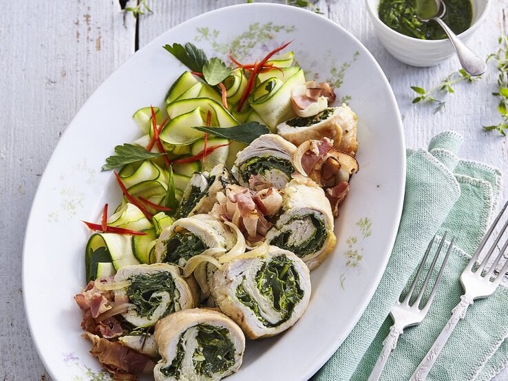 Gefüllte Putenröllchen mit Spinat und Kräuterpesto,  gehobelte Zucchini, frischer Petersilie, dünn geschnittener, Chili / zwei Gabeln / eine kleine runde Form mit einer Kräutersauce