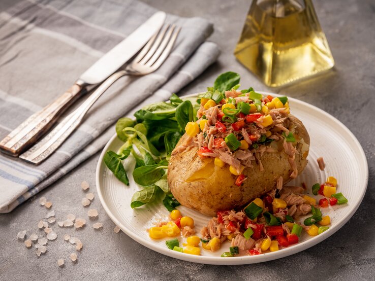 Seitliche Ansicht einer mit Thunfisch gefüllten Kartoffel auf einem runden Teller. 