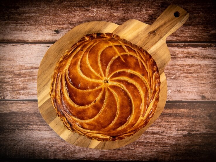 Galette de Rois auf Holzbrett und dunklem Untergrund. Draufsicht.