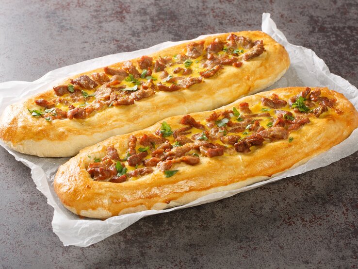 Pastrmajlija mezedonische Pizzabaguettes auf Küchenkrepp auf Steintisch. Draufsicht.