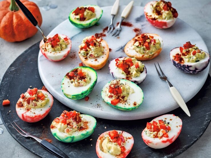 Was mögen Zombies und Monster? Ganz klar: Gefüllte Halloween-Eier! Auf einem Teller liegen gefüllte Halloween-Eier. Sie sind mit Paprika verfeinert.