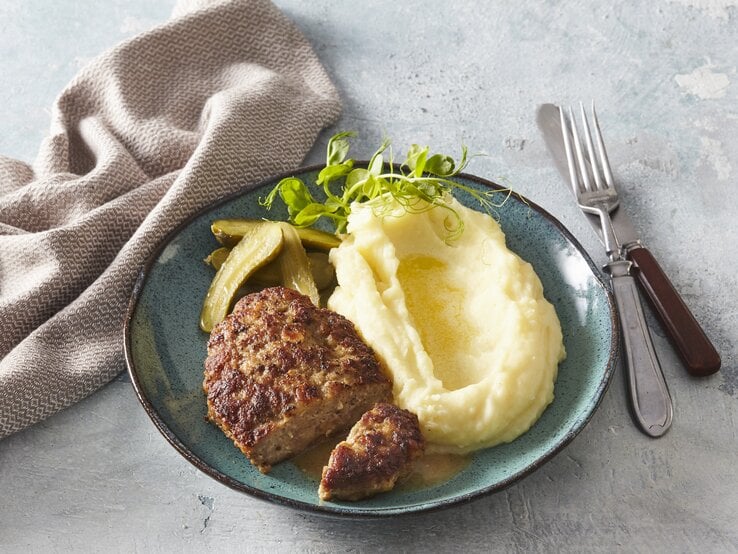 Butterfrikadellen mit Kartoffelpüree auf Teller serviert.