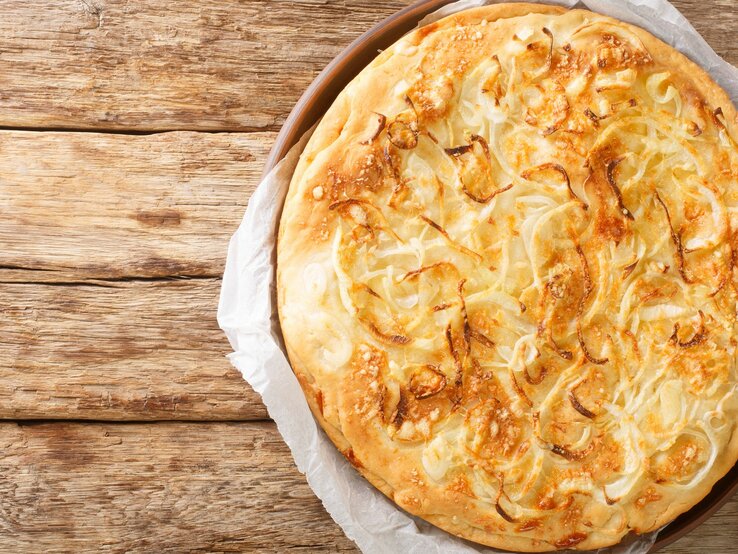 Eine Käsepizza auf einem Holztisch direkt von oben fotografiert.