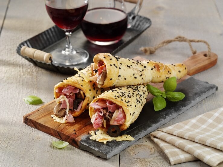 Drei Pizza-Hörnchen mit Schinken serviert.