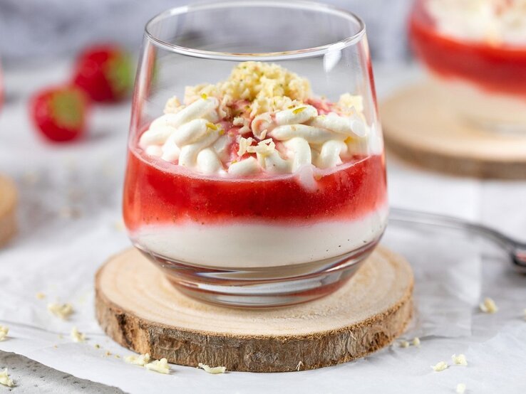 Spaghetti-Eis-Erdbeersauce In einem Glas ist ein Spaghetti-Eis mit Mascarpone und Erdbeersauce angerichtet. Es ist mit weißer Schokolade bestreut.