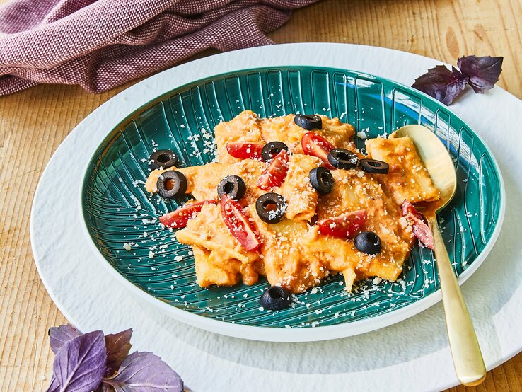 Rigatoni-Thunfisch-Auflauf mit schwarzen Oliven auf Teller serviert.