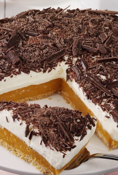 Auf einem Teller liegt eine Aprikosen-Joghurt-Torte ohne Backen. Sie ist mit Schokoraspeln bestreut.