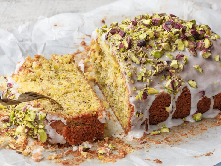 Ein angeschnittener Pistazien-Zitronenkuchen aus der Kastenform.