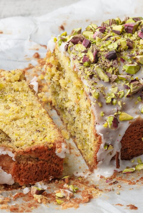 Ein angeschnittener Pistazien-Zitronenkuchen aus der Kastenform.