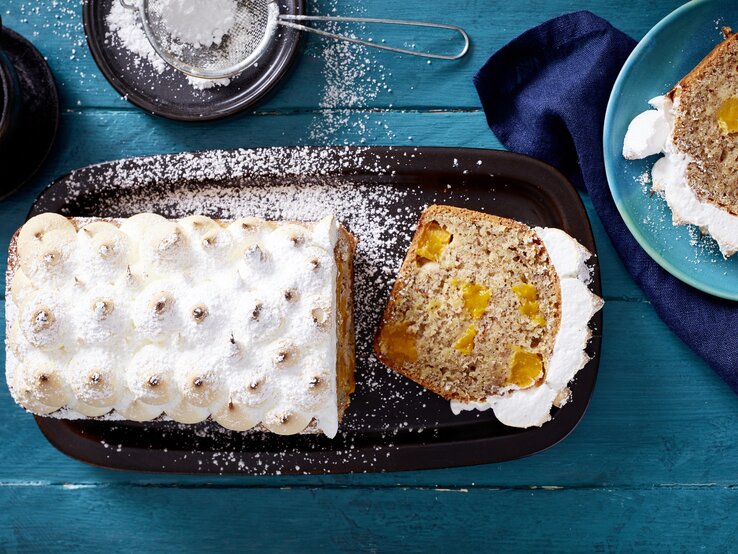 Der Mango-Baiser-Kuchen direkt von oben auf einem blauen Holztisch fotografiert.