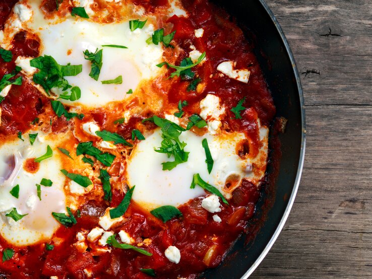 Draufsicht auf eine runde Pfanne gefüllt mit Gemüse und Ei, auch Shakshuka genannt,