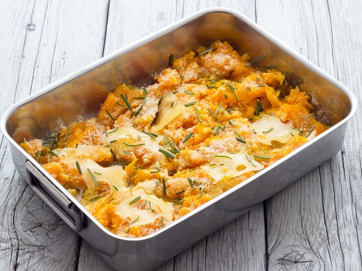 Blecherne Auflaufform gefüllt mit Kürbisauflauf und Parmesan.
