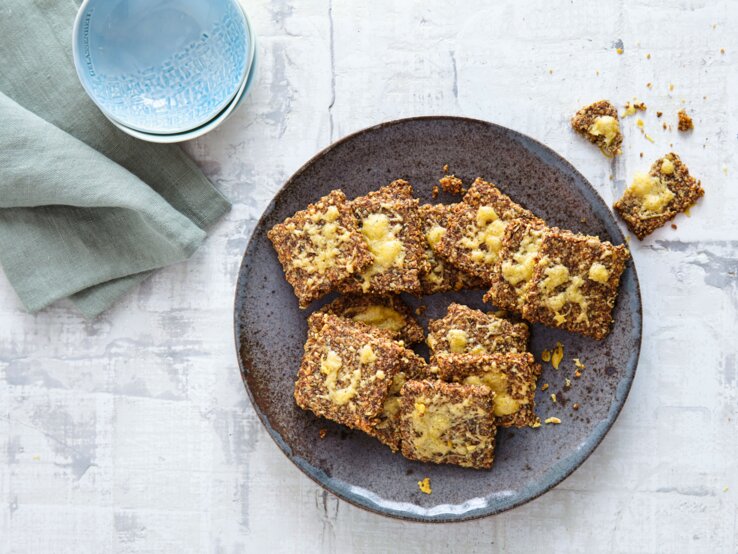 Low-Carb-Knäckebrot Ein schwarzer Teller mit dem Knäckebrot direkt von oben fotografiert.