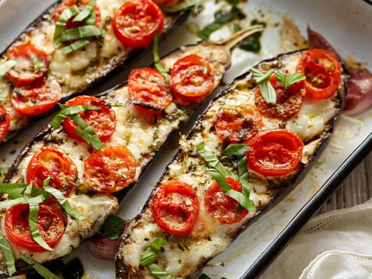gebackene Auberginenscheiben belegt mit Tomate, Käse und Basilikum.