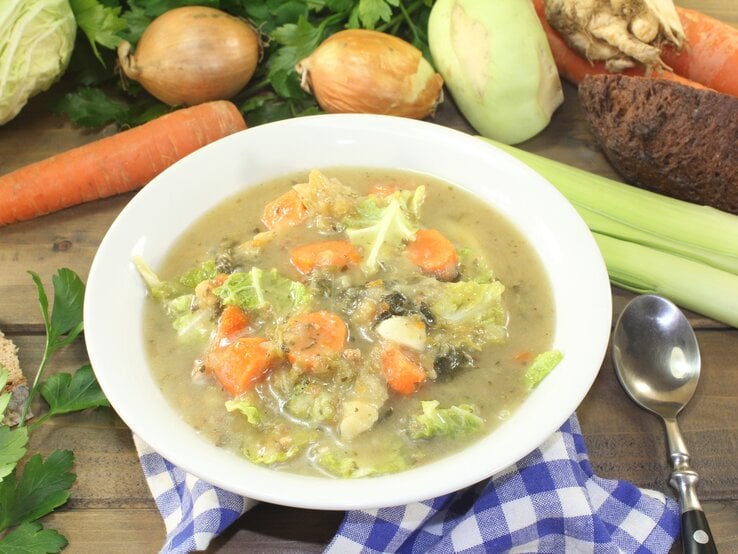 Wirsing-Kartoffel-Eintopf Wirsing-Kartoffel-Eintopf in einem Teller / Drumherum frisches Suppengemüse / Draufsicht, schräg