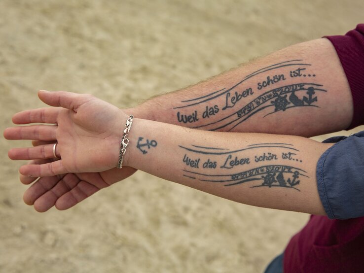Kristina und Holger haben sich gemeinsam tattowieren lassen: "Weil das Leben schön ist...". Der Spruch stammt von einer Weinsorte, die das Liebespaar gerne gemeinsam trinkt. | © Guido Ohlenbostel 24036_220429_GO_Inselliebe_0080.jpg | © Guido Ohlenbostel