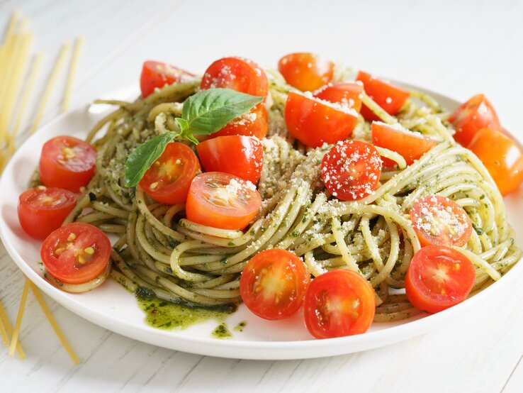 Spaghettisalat mit Pesto und Tomaten Pesto-Spaghetti-Salat mit Tomaten auf weißem Teller.