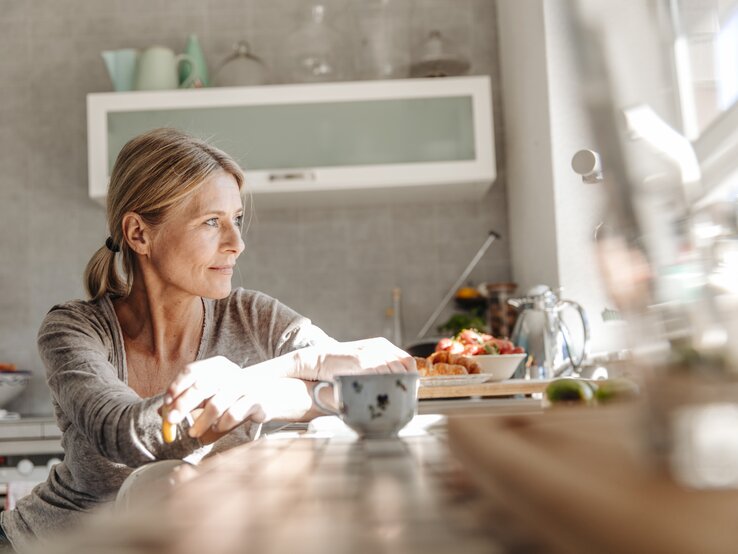 Frau sitzt am Fenster mit einer Tasse Tee  | © Gettyimages/Westend61