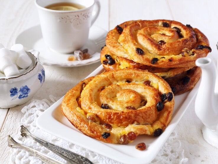 Rosinenschnecken Mehrere runde Gebäckstücke mit Rosinen auf einem langen, eckigen Teller.