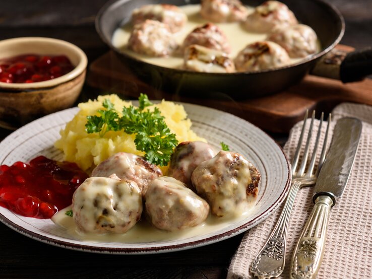 Rustikaler Teller mit Kartoffeln, Preiselbeersoße, Hackbällchen "Köttbullar" und cremiger Soße. 