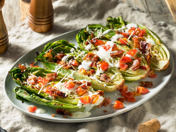 Seitliche Ansicht auf einen Teller mit gegrilltem Romanasalat. 