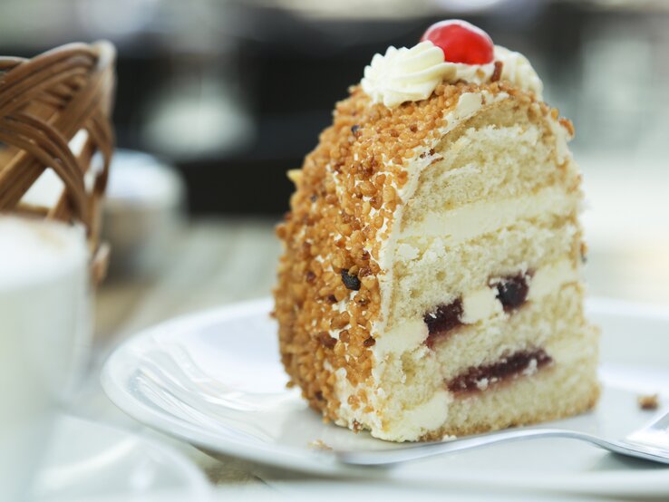 Ein Stück vom Frankfurter Kranz auf einem weißen Teller nah und von der Seite fotografiert.