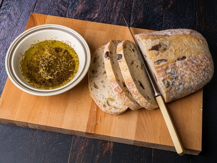 Ein Laib griechisches Olivenbrot auf einem Holzbrett.