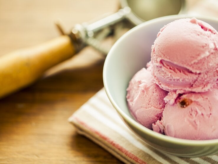 Erdbeer-Käsekuchen-Eis Mehrere Bällchen Erdbeer-Käsekuchen-Eis in einer weißen Schale.