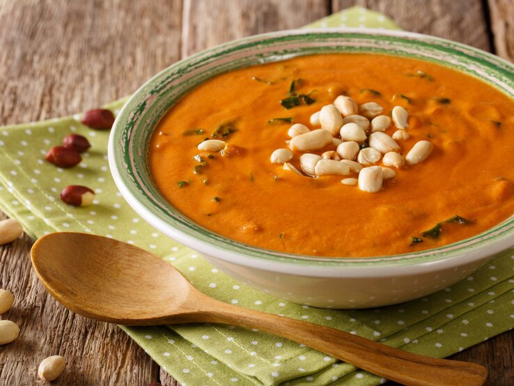 Seitliche Ansicht auf eine Schüssel afrikanische Erdnusssuppe auf Holztisch.