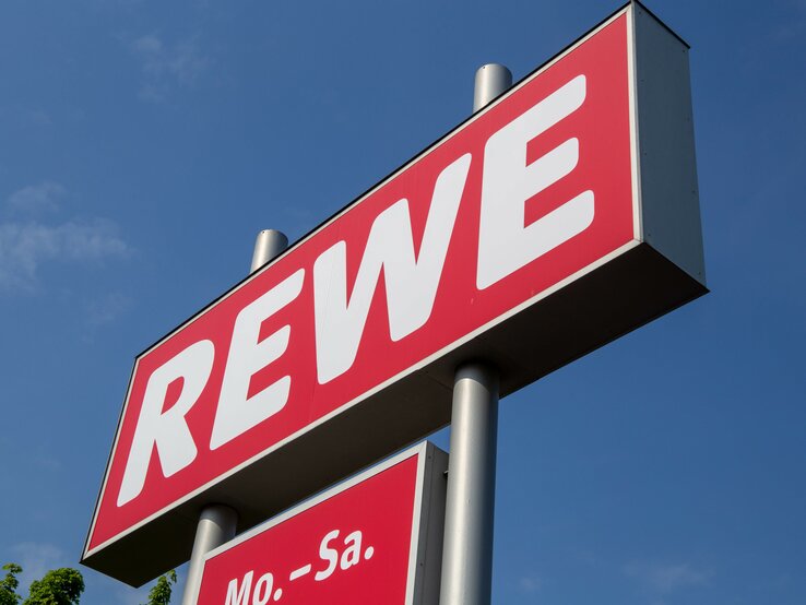 Das Rewe-Logo vor dem blauen Himmel