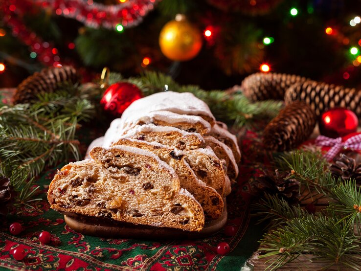 Ein angeschnittener Stollen umringt von vielen weihnachtlichen Deko-Elementen. 