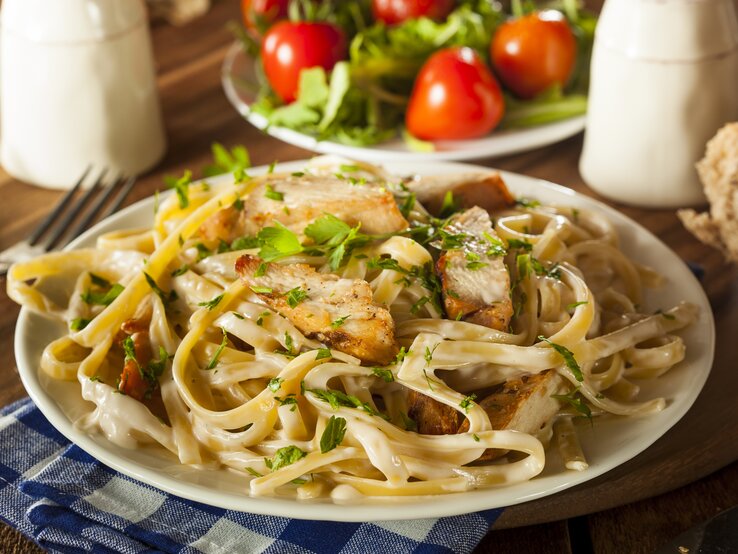 Ein Teller mit Pasta in Hähnchen-Sahnesoße, bestreut mit Kräutern. 