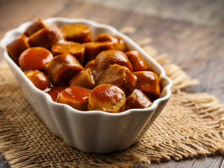 Ein Bild von einem weißen Keramikschale gefüllt mit Berliner Curry-Wurst.